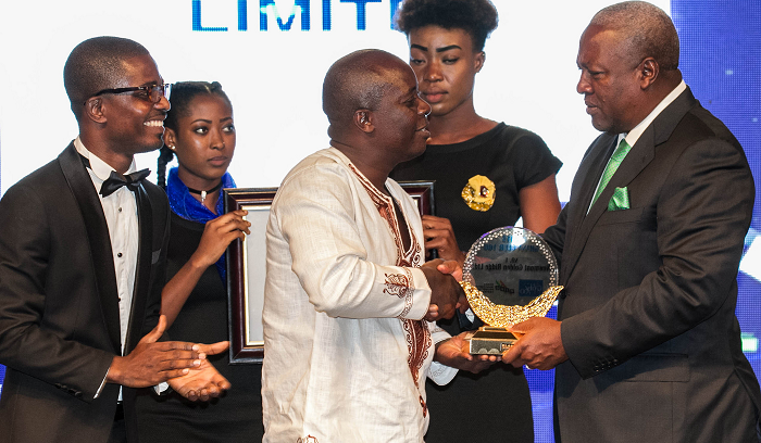 President Mahama presenting top Ghana Club 100 award to a representative of Newmont Golden Ridge .