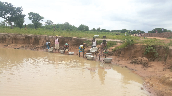  Women fetching the milky-brown water at the artificial dam site for domestic use
