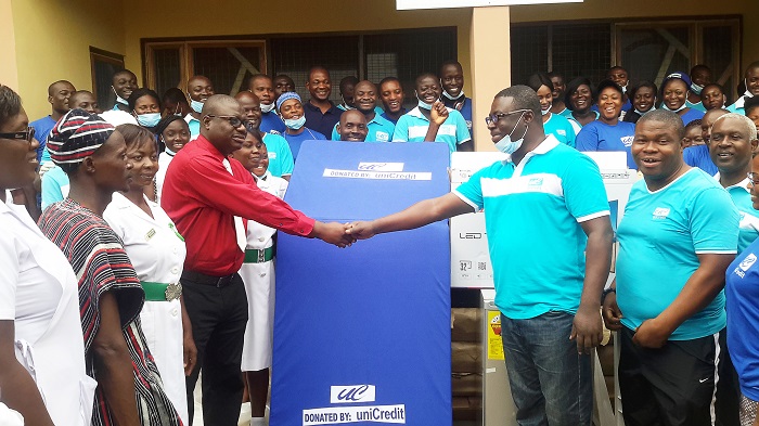 Dr Amo-Mensah (4th from left, front) in a handshake with Mr Asiamah-Yeboah. Those with them are staffs of uniCredit and the Kaneshie Polyclinic.