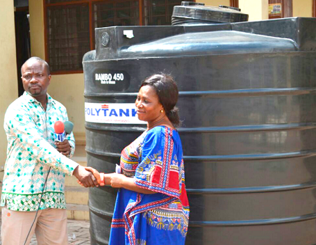 Mr Angenu (left) presenting a water tank to a beneficiary