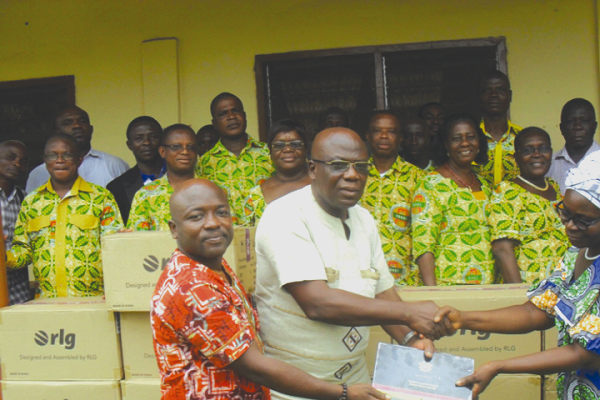 The Municipal Chief Executive of  Lower Manya Krobo, Mr Jacob Frederick Kwame Acolatse (middle) handing over some  laptop computers  to  the Municipal  Education Director.