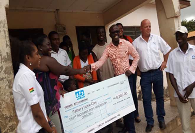 Mr Micheal Preprah (3rd right), Finance Manager of TETRA B.V, presenting the cheque to Madam Yamoah while staff of the company look on