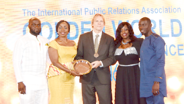 Ms Esther Cobbah (2nd left), CEO of Stratcomm Africa, receiving the award from an official of the organisers while some officers of Stratcomm look on.