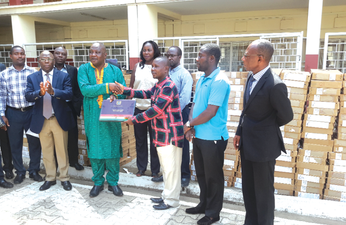   Mr Kyeremeh (left) presenting one of the laptops to Mr Antwi, while some officials from the ministry look on