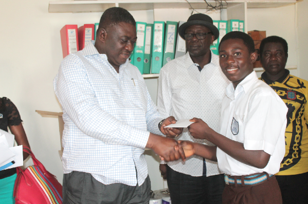 Mr William Yeboah (left), a Socio-Economic Analyst, presenting a cheque to Mr Michael Abbey (right), a beneficiary of the scholarship with Mr Ronald Akosah (2nd left) looking on.
