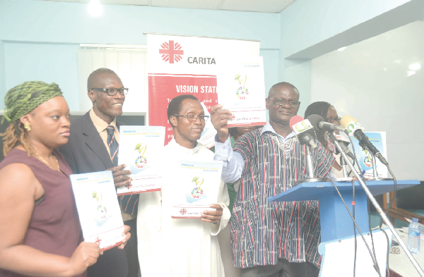Dr Kwaku Adjei-Fosu (in smock) of the National Development Planning  Commission launching the  report at the Press Centre in Accra. With him are  Mr Samuel Zan Akologo (2nd left), Executive Secretary of the Caritas Ghana the some invited guests.