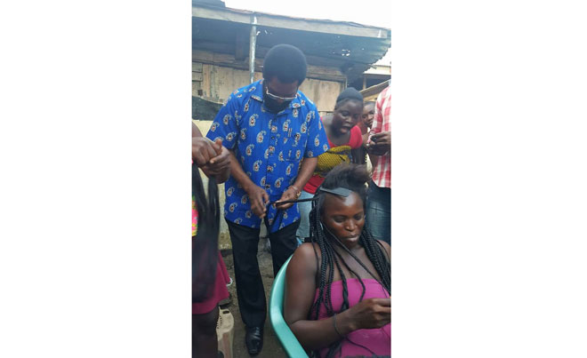 Accra Mayor, Alfred Oko Vanderpuije has been pictured braiding a woman’s hair