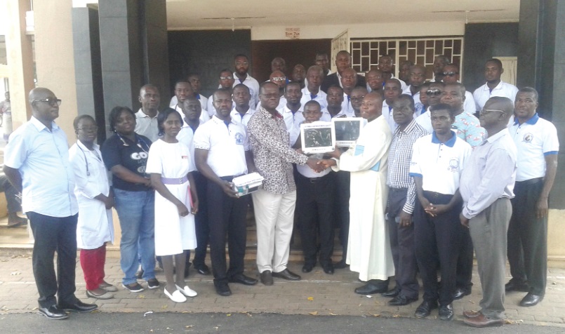 • Rev. Fr John Opoku, the Parish Priest of the Saint Paul's Catholic church (in cassock), presenting the equipment to Prof. Addo-Yobo while other members look on