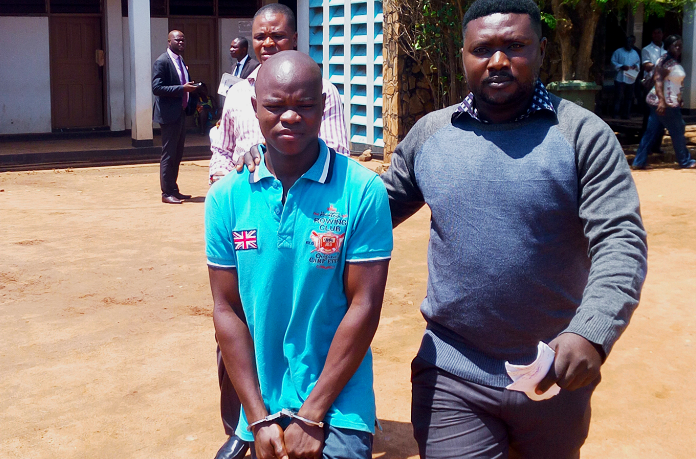   Lucas Agboyie (in handcuffs) being led out of the court premises by a police officer after proceedings