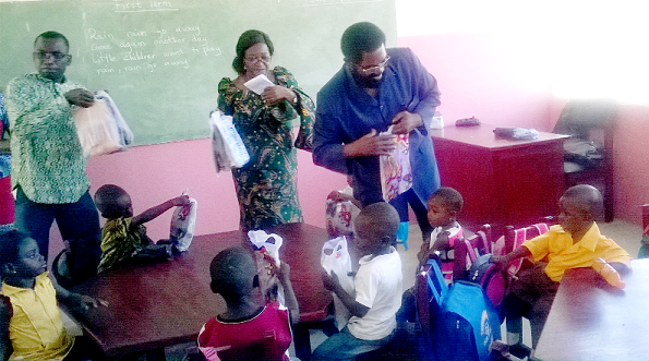 Dr Alfred Okoe Vanderpuije (arrowed) distributing some educational items to the children