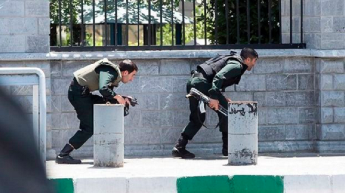 Iranian forces take cover as they surround the parliament building