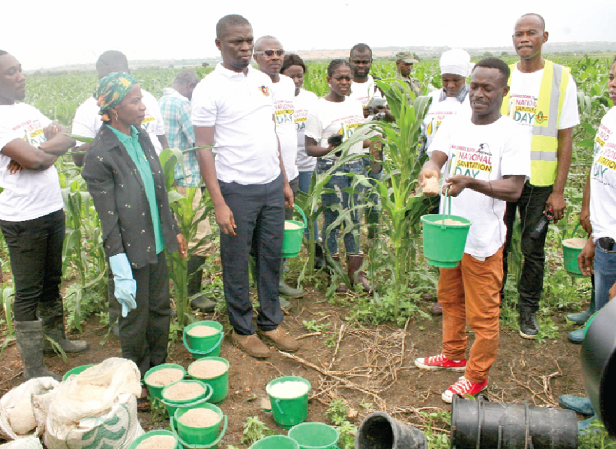 Mr Moses Amaku Kudjo (3rd right), Assistant Project Director of National Service Agricultural Project, demonstrating how to apply the fertiliser. Looking on is Mr Yussif Mustafa (4th left), the Executive Director of the NSS