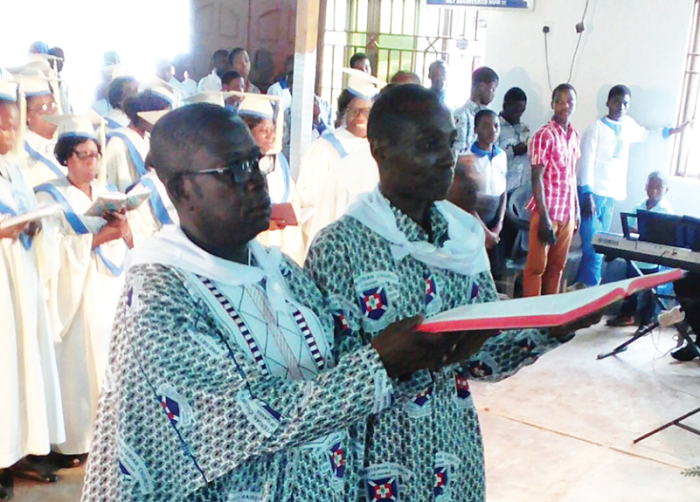  Catechist Nii Djartei Abbey (left) and Mr Ransford Michael Obuobi, Senior Presbyter, holding the Bible presented to the Congregation while a section of the congregation looks on.