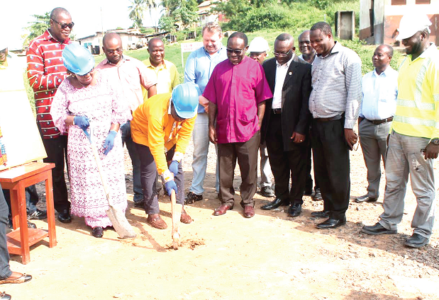 Mr K.K. Sam (with pickaxe joined by Mrs Alberta Cudjoe to break grounds to officially start the project. Looking on are Ghacem officials and dignitaries present