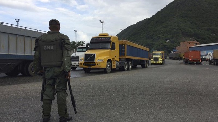 A National Guard soldier watches over cargo trucks leaving the port in Puerto Cabello in Venezuela [Ricardo Nunes/AP]