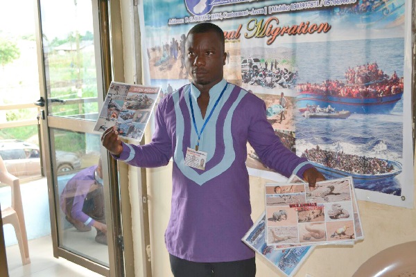 • Mr Innocent Donkor displaying pictures of the danger of migration to participants in the event