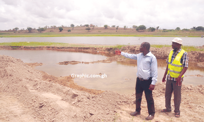 An official of GIDA explaining a point on the level of siltation of the Okyereko Dam to the Graphic reporter. 