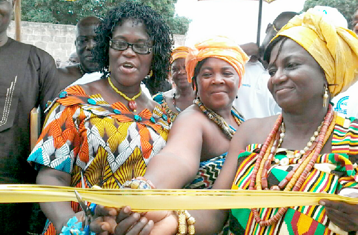 Madam Angelina Attakey (left),  an education officer at the Kpando Municipality, being assisted by Madam Comfort Addai (right) to cut the tape 