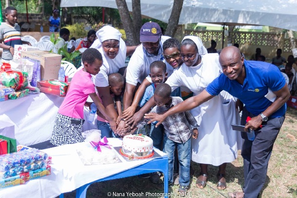 Rotarian President William Alomatu (in cap) cuts cake with other Rotarians and sisters and  children of the home