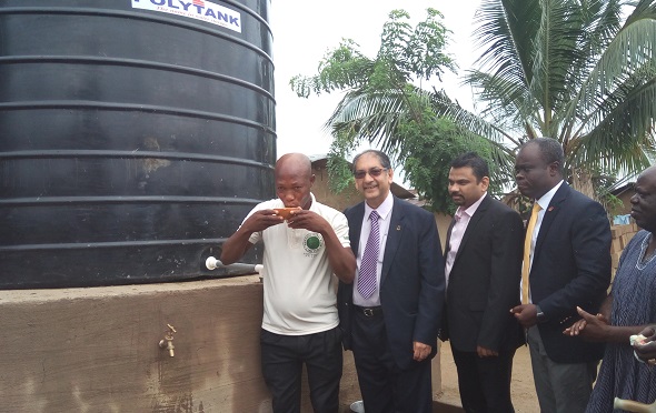 Mr Joseph Y. Konnor drinking fresh water from the borehole, while Mr Mahesh Mahtani and others look on