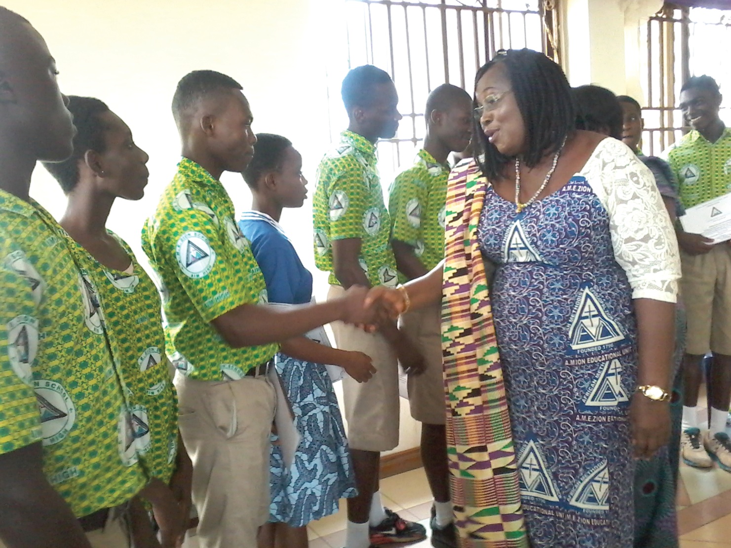 Mrs Evelyn Boakye-Mensah Zormelo, General Manager of the AME Zion Schools, shaking hands with one of the students while the others look on