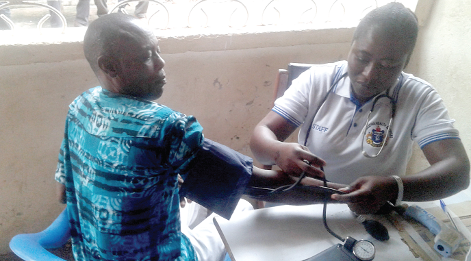 Madam Janet Kumi checking the blood pressure of the Chief of Daban during the health screening in Kumasi