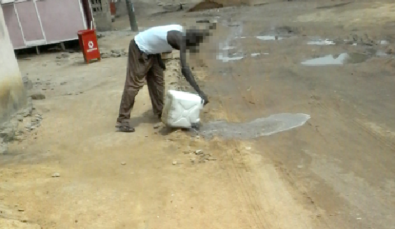  A  resident in Kasoa pouring wast water onto the streets in Kasoa 