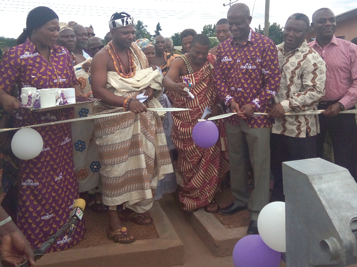 Nana Amoah II (3rd left), the Chief of Akpafu Mempeasem, cutting the tape to inaugurate one of the boreholes. With him are Mr Osei Asafo-Adjei (3rd right) and other dignitaries.