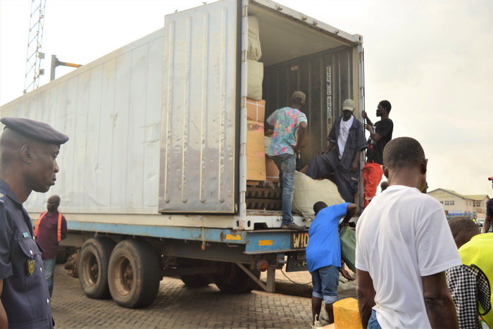 Casual labourers packing the items back into the container after the examination. 