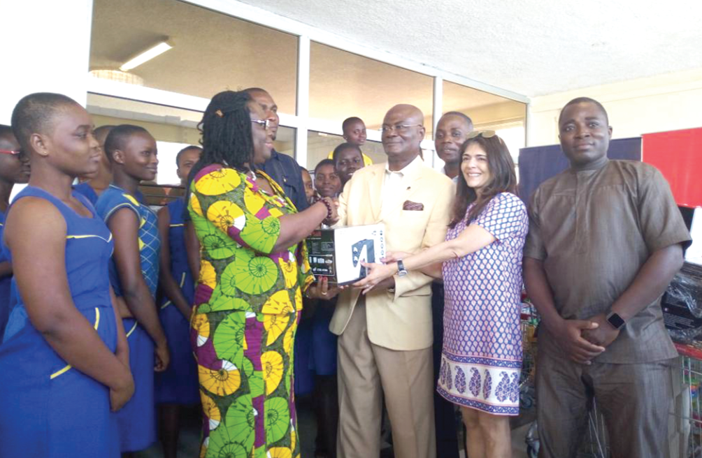 Mr Godwin Avenorgbo ( arrowed) and Mrs Sonya Sadhwani (2nd right), Director of Brand Management of Melcom, presenting one of the items to Madam Cynthia Essibrey-Annan while some of the students and teachers look on
