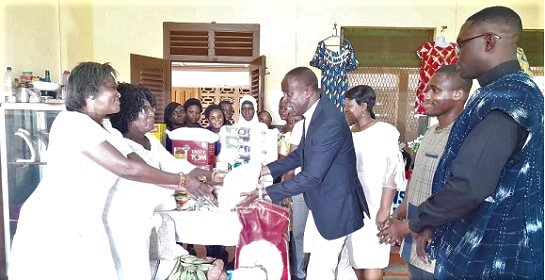 Very Rev. Emmanuel Evans Essien (4th from right), the Superintendent Minister of the New Aplaku Circuit, presenting the items to Rebecca Nettey, the Accra Diocesan Coordinator on Gender and Family Life Issues, while others look on