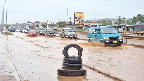 Vehicles driving slowly through flood waters on a section of the Ofankor-Taifa road causing heavy vehicular congestion on the stretch