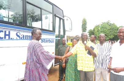  • Elder Charles Okrah (right, with microphone), PTA chairman of the school,  handing over the bus to Mr Sasah  (in smock), headmaster