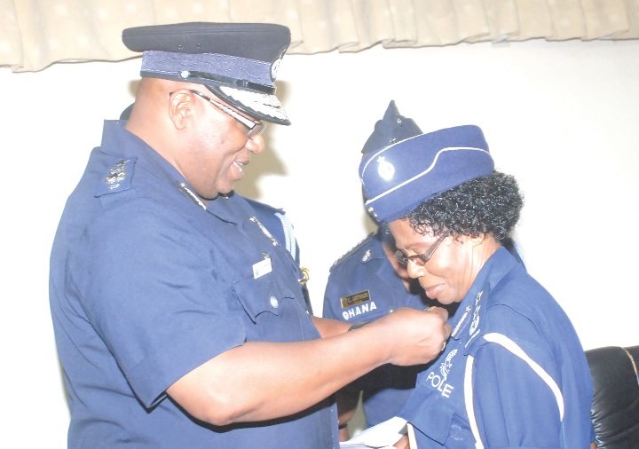 Mr Mohammed Ahmed Alhassan(left), Inspector General of Police, decorating DCOP Joana Osei Poku, Director General, Human Resource Develpment, with the new police badge after its launch in Accra.
