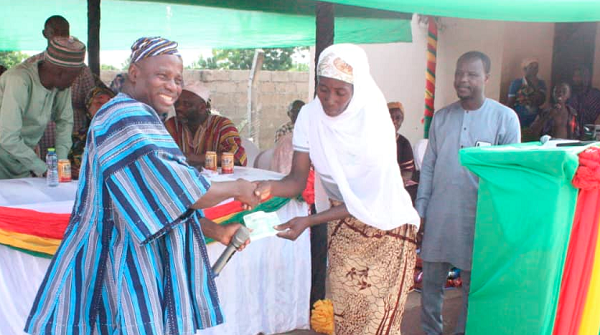Yidana Zakaria, the North East Regional Minister, presenting a cheque to a beneficiary