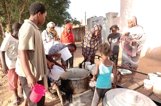 Displaced Sudanese families waiting  to receive food from a charity kitchen, as a year of war between two generals has driven more than 5.8 million people into poverty