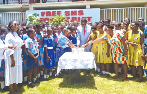 Dr Yaw Osei Adutwum, Minister of Education, being supported by schoolchildren to cut his birthday cake