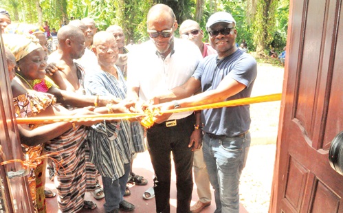 Samuel Ledo (right), an indigene, being assisted by other stakeholders of Klefe-Demete to perform the tape-cutting ceremony. INSET: The 24-seater water closet facility