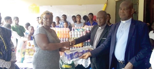  Rev. Emmanuel Oklemey Tettey (2nd from right), the Somanya District Pastor of PCG, presenting the items to Christabel Adakwah, the foster mother of the orphanage 