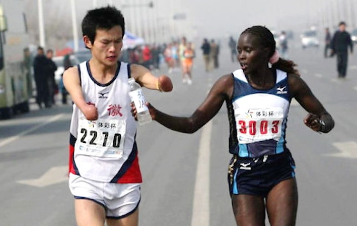 A Kenyan elite runner passes water to a disabled fellow athlete, slowing her time and costing her first place.