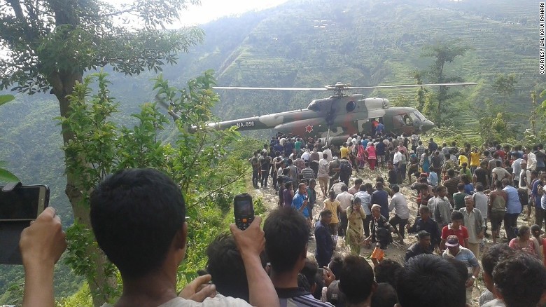 A crowd watches as rescuers carry the injured from a bus wreck to a helicopter Monday.