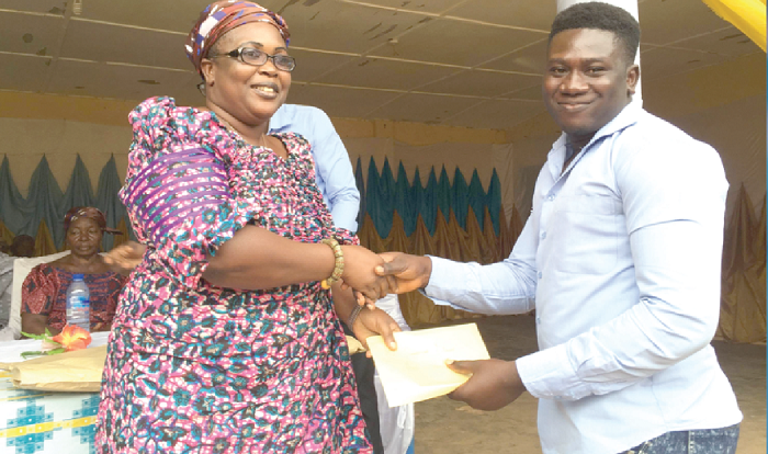 Obaahemaa Adwoa Kwantwiwaa of Bompieso, presenting a scholarship award letter to Sabastine Diaw (right), a beneficiary.