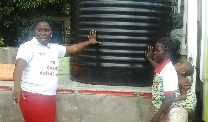 Ms Rosemary Ladzi receiving the water-tank.