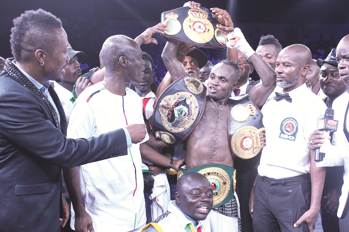  Game Boy displays his belts while the Minister of Youth and Sports, Nii Lante Vanderpuye (left), and referee Roger Barnor (right) look on