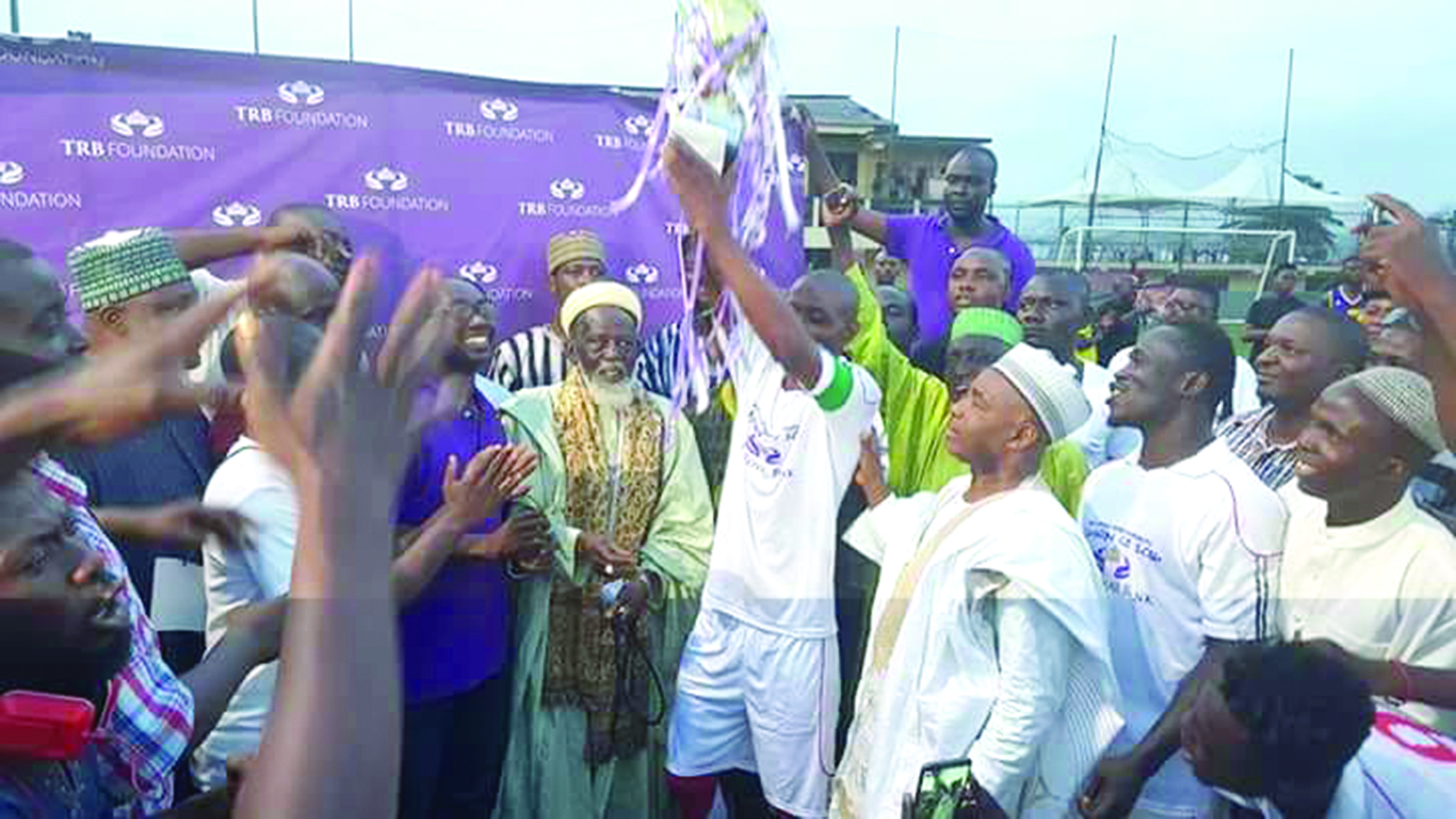 The skipper of Ashaiman holds aloft the Sharubutu Cup to the admiration of the National Chief Imam