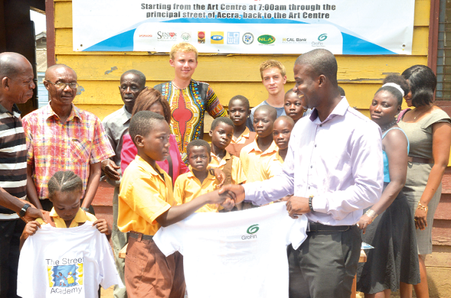 Mr Abraham Mensa-Belley presenting  shirts to one of the children of the academy