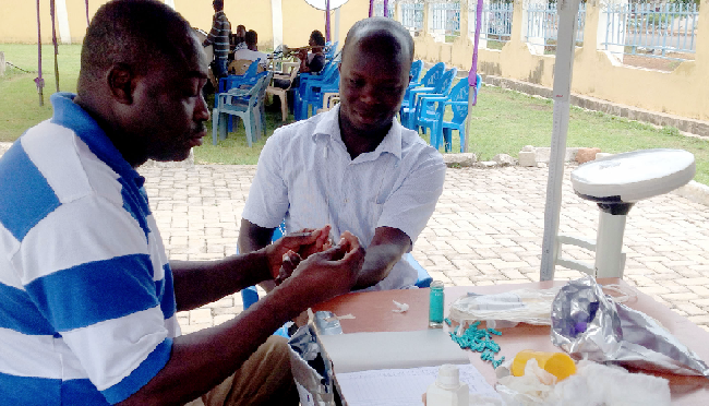 Mr Emmanuel Mahama Amin taking blood sample from a donor for screening before the donation