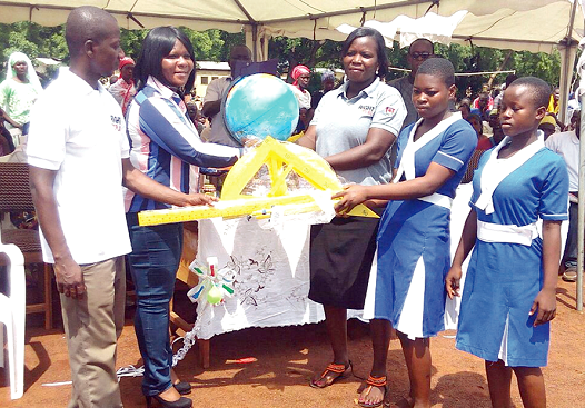  Mrs Ethel Sakitey (2nd left) being assisted by Samuel Oppong Kwabiah (left), Project Coordinator of Right To Play, to hand over some educational materials to Madam Jennifer Bittor at the durbar.