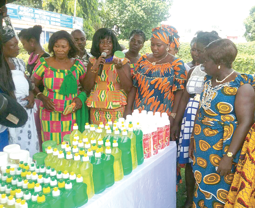 The CEO of OWEC, Mrs Comfort Anima Opoku (with microphone), inspecting items produced by the trainees after a month training