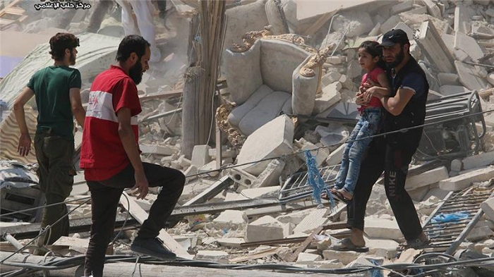 A Syrian man carries a girl from a destroyed building after barrel bombs were dropped in this August 2016 file photo [Aleppo Media Center via AP]